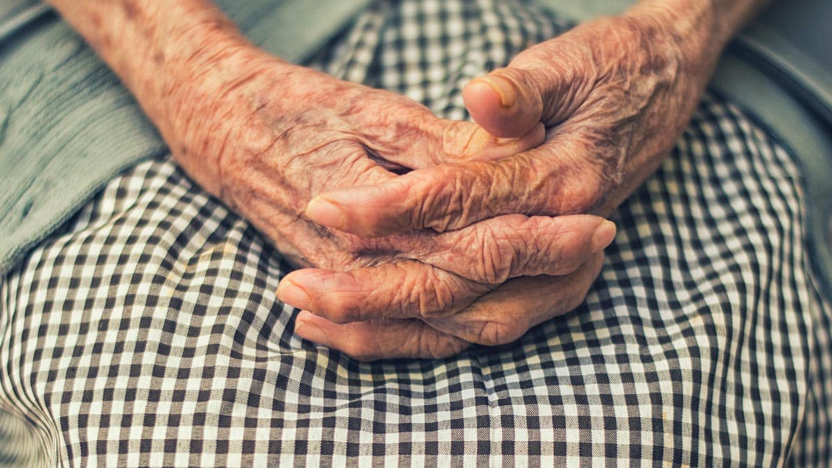 Elderly woman's hands clasped together on her lap