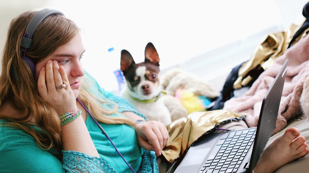 Young woman using a laptop, sitting with a small dog