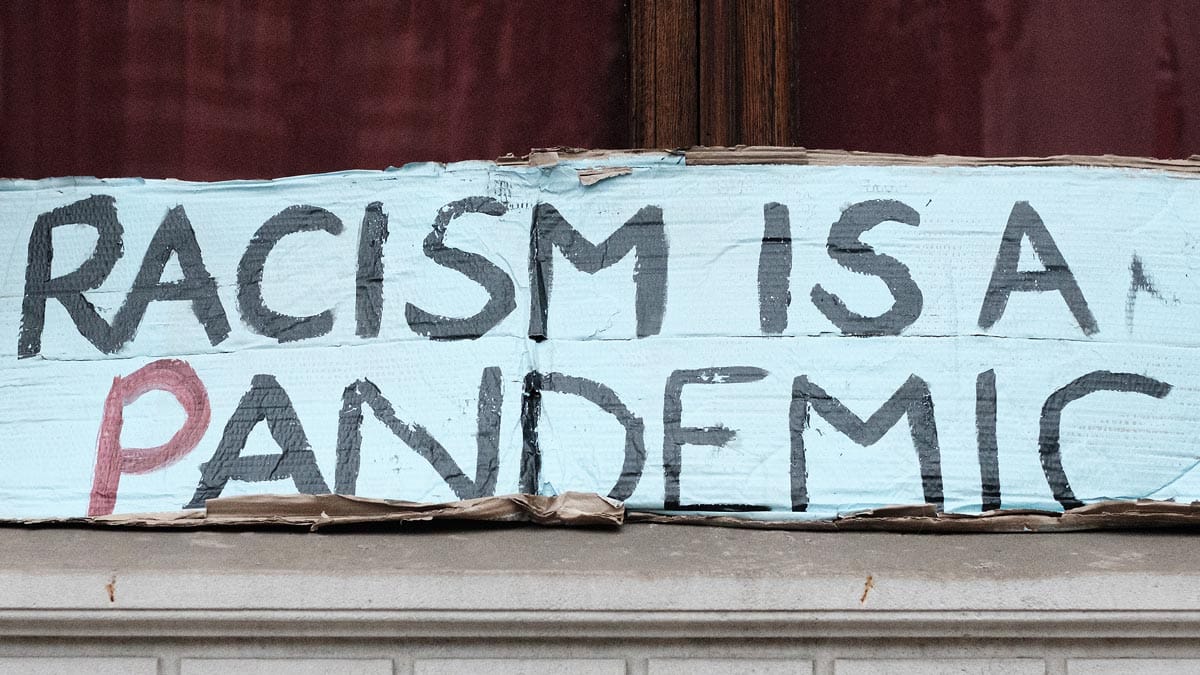 Hand written banner stating 'Racism is a pandemic'