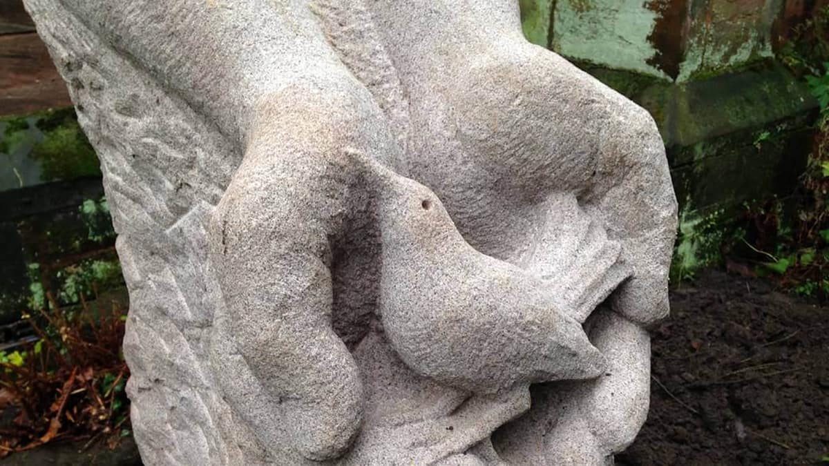 Stone carving of two hands holding a bird