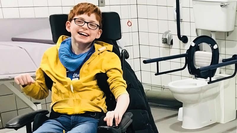 Smiling boy in wheelchair, inside a Changing Places facility