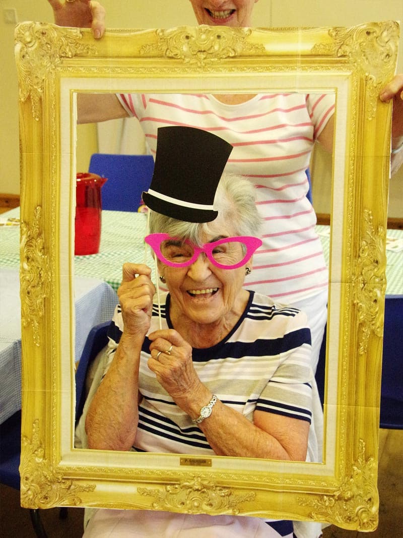 Elderley woman poses ith fun hat and spectacles